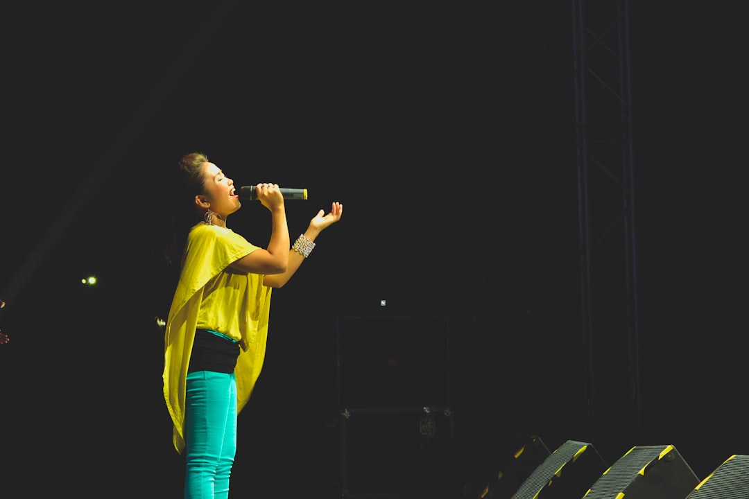 Photo by MD Duran woman holding a microphone performing on stage